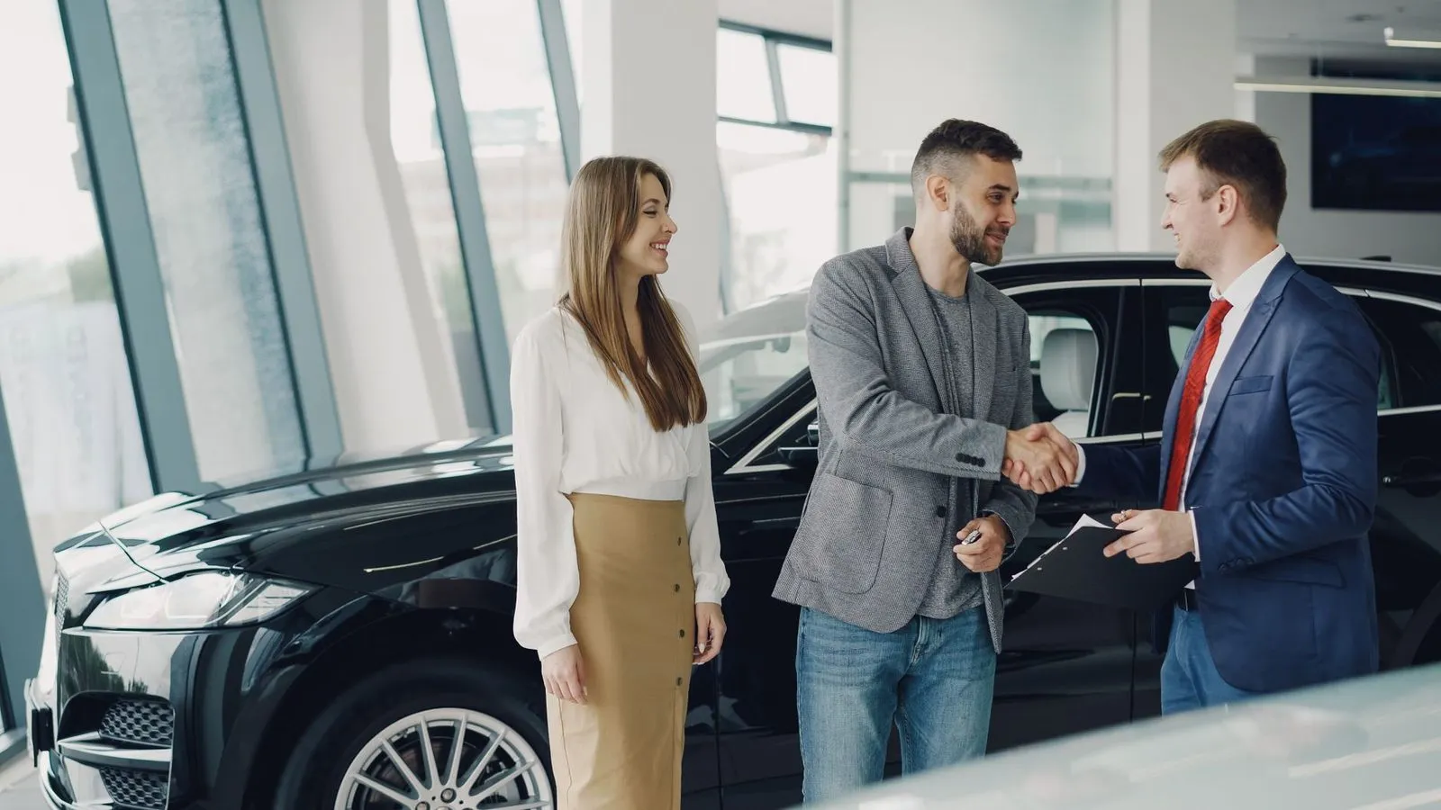 An appraiser shaking hands with a customer next to a vehicle