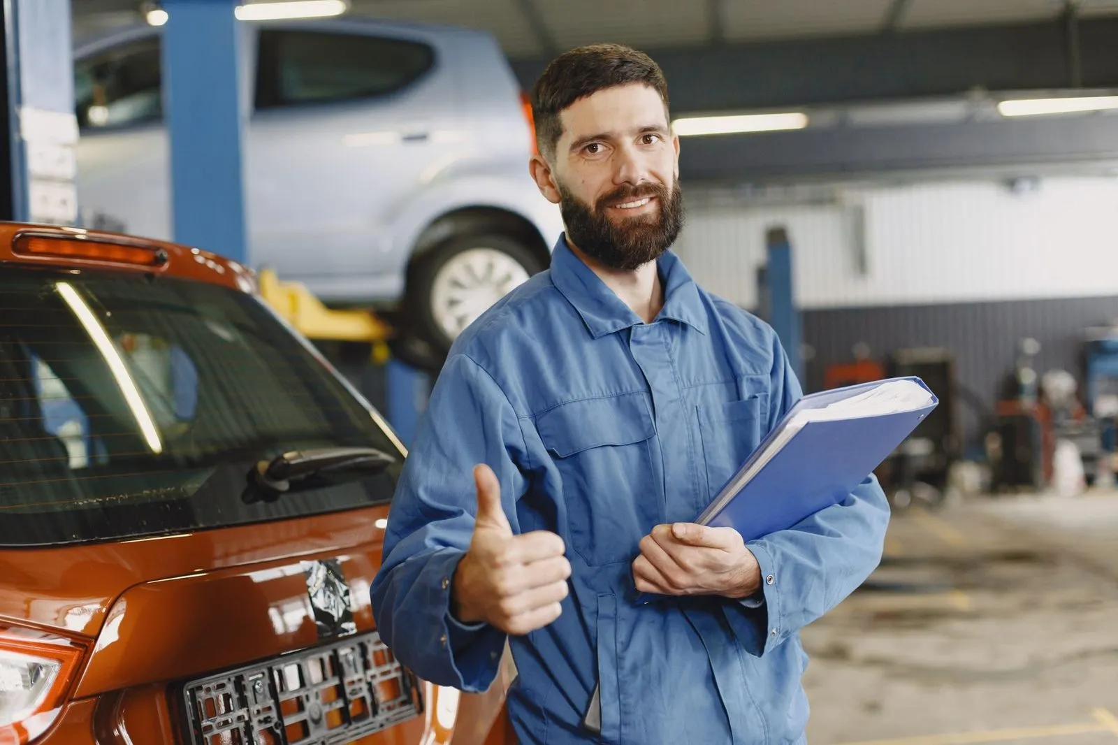 A mechanic holding a clipboard next to a vehicle